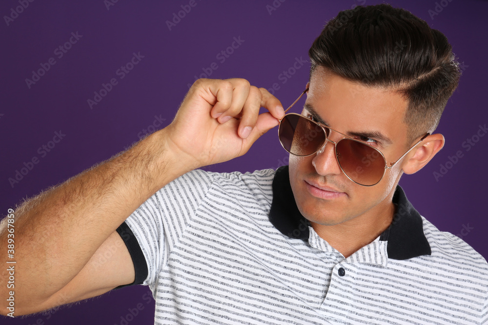 Handsome man wearing sunglasses on purple background Handsome man wearing sunglasses on purple background