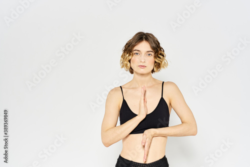 sporty woman in black jeans and a t-shirt doing exercises in a bright room