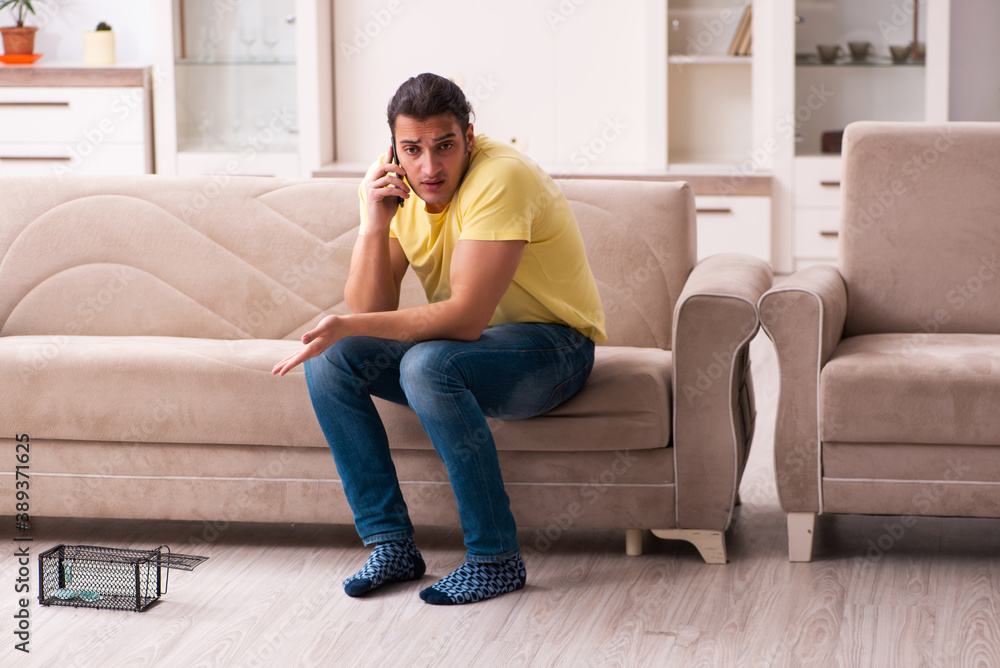 Young man and mousetrap at home Young man and mousetrap at home