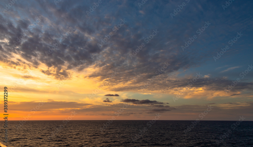 Sunset and dramatic set of clouds drifting over the tropical waters of the Caribbean Sea are lit by the last moments of daylight. Sunset and dramatic set of clouds drifting over the tropical waters of the Caribbean Sea are lit by the last moments of daylight.