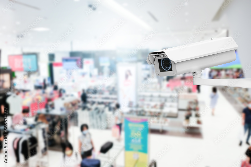 Obraz premium Modern public CCTV camera with blur interior shopping mall background. Recording cameras for monitoring all day and night. Concept of surveillance and monitoring with copy space.