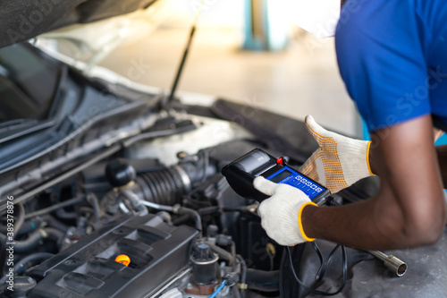Expertise mechanic working in automobile repair garage. battery inspection. Battery Capacity Tester Voltmeter © NVB Stocker