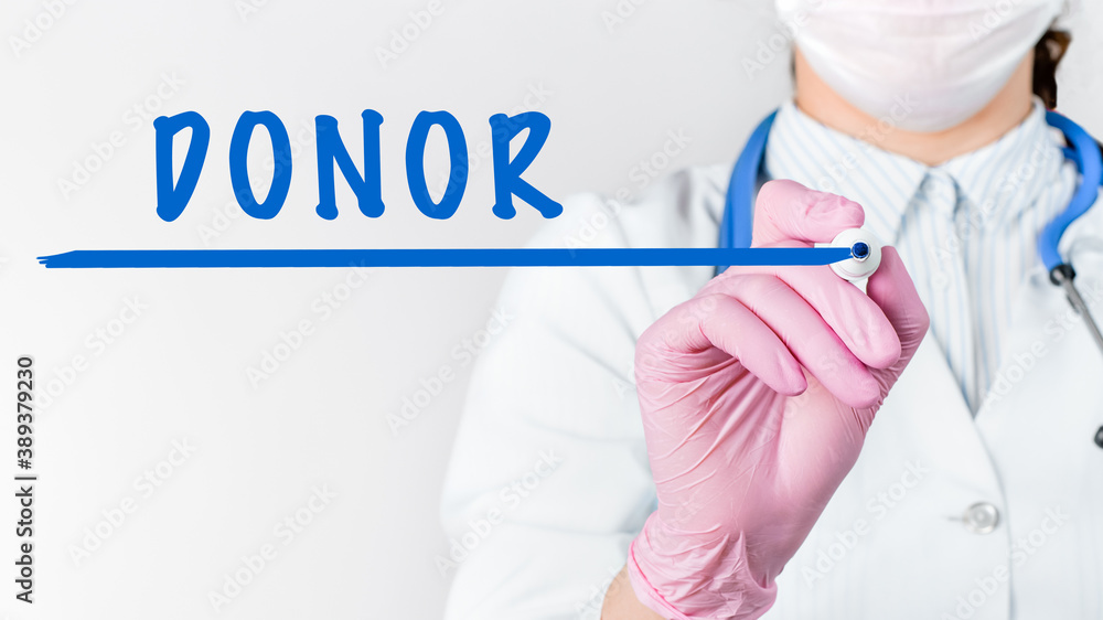 Close up female doctor writing word DONOR with marker. Medical concept Close up female doctor writing word DONOR with marker. Medical concept