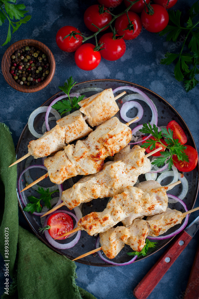 Chicken skewers on wooden skewers with vegetables on a ceramic plate, selective focus Chicken skewers on wooden skewers with vegetables on a ceramic plate, selective focus