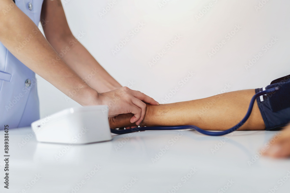 Fototapeta premium A young nurse is measuring the pressure of a patient who is admitted to the hospital.