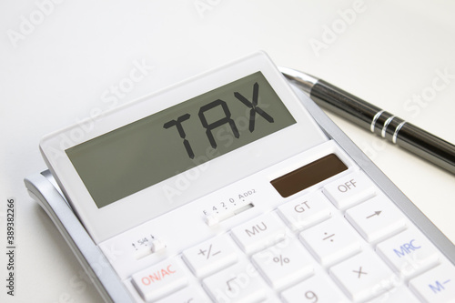 The white calculator on white background and word tax in display