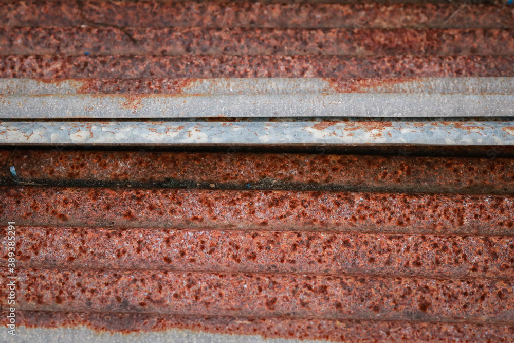 Sharp edges of the rusty metal sheets placed on the floor. Old aged weathered rusty galvanized corrugated iron sheet roof of abandoned mood. selective focus blur background. Vintage. Sharp edges of the rusty metal sheets placed on the floor. Old aged weathered rusty galvanized corrugated iron sheet roof of abandoned mood. selective focus blur background. Vintage.