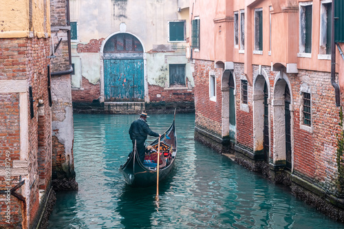 Gondola on a foggy day sailing on narrow canals - Venice, Italy