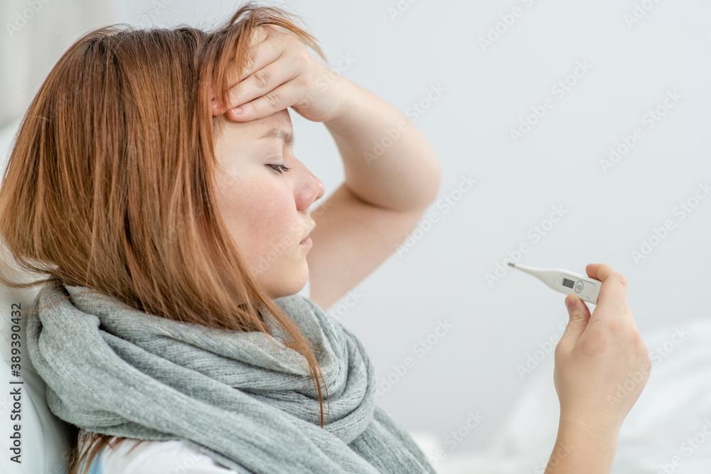 Sick young boy checks the temperature with a thermometer at home Sick young boy checks the temperature with a thermometer at home
