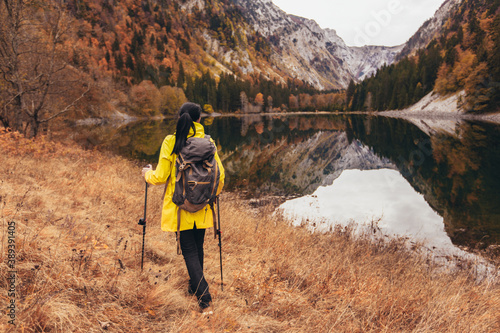 Woman with backpack and raincoat hiking Lifestyle adventure concept forest and lake on background active vacations into the wild