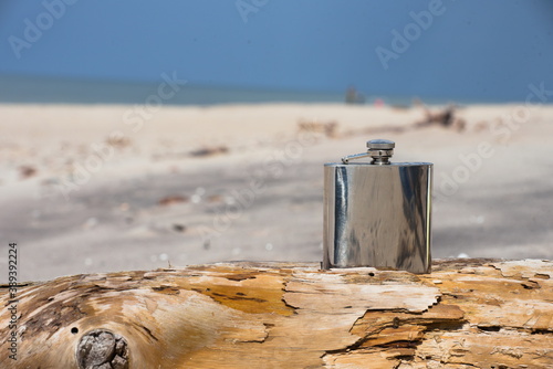 Fototapeta Naklejka Na Ścianę i Meble -  Hip flask on a wooden beam lying on the beach.