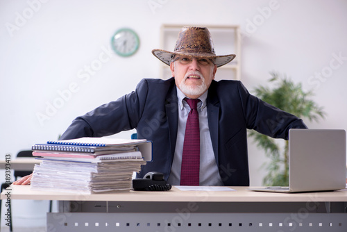 Принти на полотні Funny old boss in cowboy hat in the office