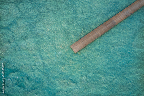 High altitude aerial view of a wooden pier on turquoise transparent water. Copy space. aerial view of wooden jetty