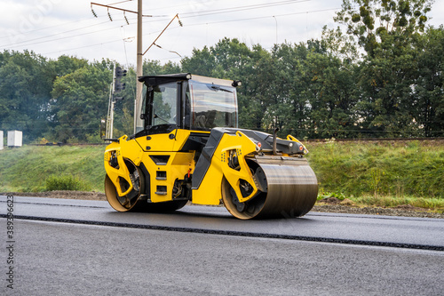 Konstfotografi Asphalt road roller with heavy vibration roller compactor press new hot asphalt on the roadway on a road construction site