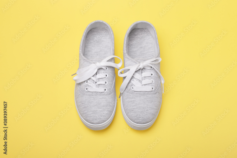 Pair of grey sneakers with tied shoelaces on yellow background. Pair of grey sneakers with tied shoelaces on yellow background.