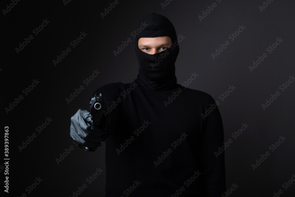 robber in balaclava with weapon in hand on black background robber in balaclava with weapon in hand on black background