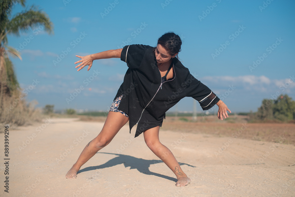 Fit woman in a dance pose. Wide shot in natural morning sunlight. Fit woman in a dance pose. Wide shot in natural morning sunlight.