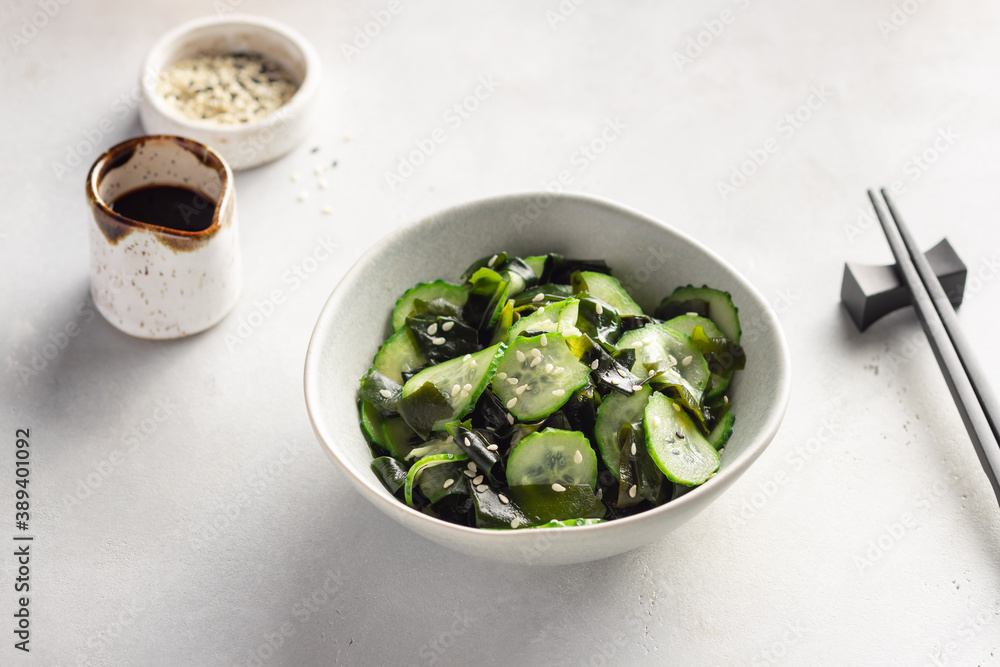 Traditional Japanese Sunomono salad with wakame seaweed, cucumbers and sesame seeds. Asian food. Gray background.