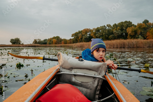 Evening kayak trip along the river in autumn. The active lifestyle of the child in the family.