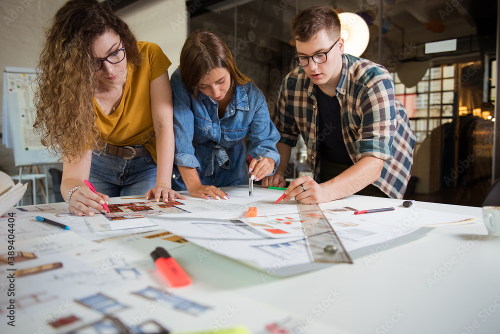 Group of designers drawing on a blueprint Group of designers drawing on a blueprint
