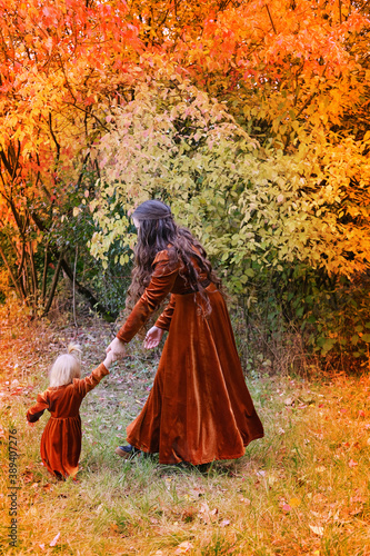 beautiful woman with a little girl in medieval vintage dresses are walking in the autumn in the park  the concept of a healthy lifestyle  good mood  family walks