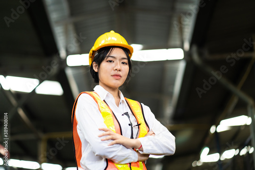 Woman worker wearing safety goggles at Metal lathe industrial manufacturing factory. portrait of cheerful young Asian woman wearing hardhat smiling happily looking at camera