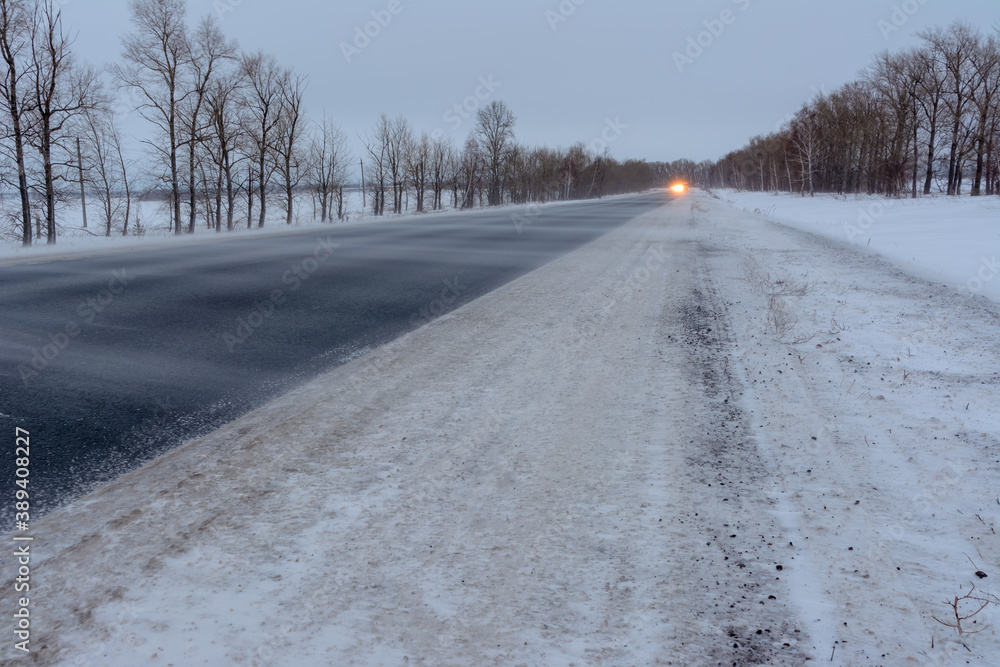 Snowstorm on the highway. Patterns on the winter highway in the form of four straight lines. Snowy road on the background of snow-covered forest. Snowstorm on the highway. Patterns on the winter highway in the form of four straight lines. Snowy road on the background of snow-covered forest.