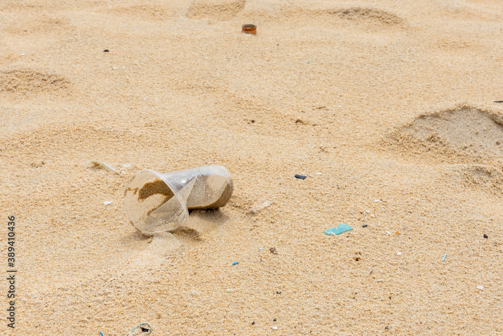 A plastic glass and other litter garbage was left on the beach. Environmental care and recycle concept. A plastic glass and other litter garbage was left on the beach. Environmental care and recycle concept.