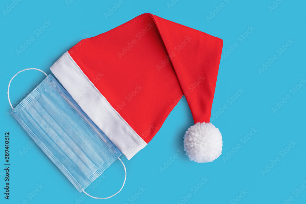 red Santa Claus hat and medical mask on blue background