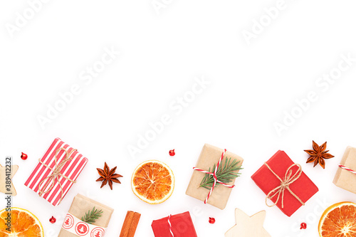 Christmas background. New year flat lay with craft red gifts, fir tree branch, dry sliced orange, anise, wooden stars, baubles, cinnamon sticks on white backgrop with copyspace.