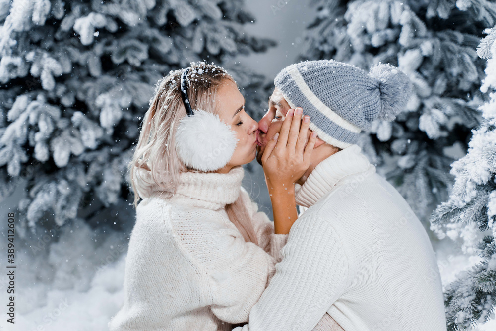Couple seat on the snow and hug, kiss, and have fun each other. Winter love story before new year celebration. Waiting for christmas gift. Happy couple weared fur headphones, hats, white sweaters. Couple seat on the snow and hug, kiss, and have fun each other. Winter love story before new year celebration. Waiting for christmas gift. Happy couple weared fur headphones, hats, white sweaters.