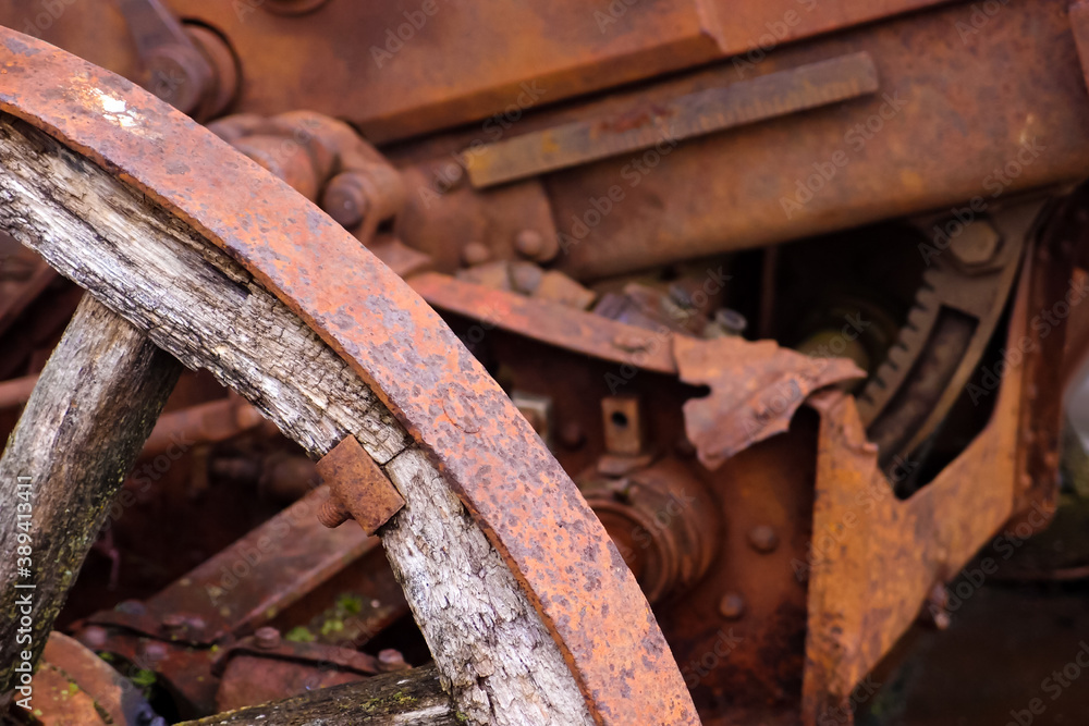 Old broken rusty tractor with wooden wheels, close-up. Ancient tractor from the 19th century