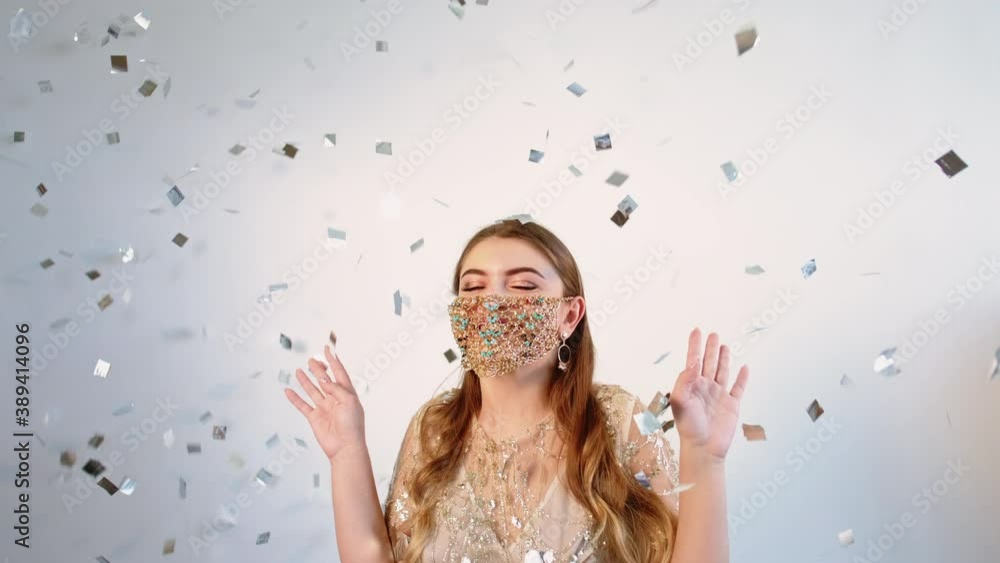 Pandemic celebration. Quarantine party. Glamour Covid-19. Amused happy brunette woman in handmade gold chain face mask enjoying confetti rain on light neutral background set of 2. Pandemic celebration. Quarantine party. Glamour Covid-19. Amused happy brunette woman in handmade gold chain face mask enjoying confetti rain on light neutral background set of 2.
