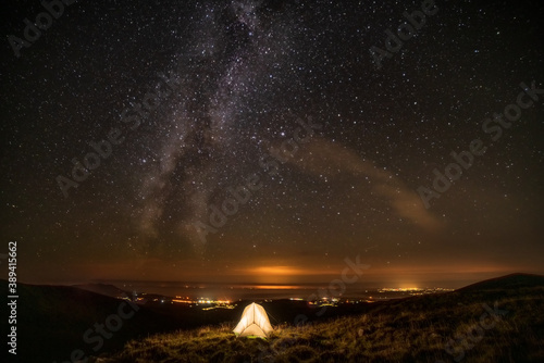 Milky way and solo wildcamping tent on grassy summit, Nanttle, Wales, UK.