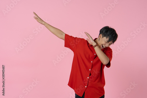 portrait of young handsome hipster asian man with smiling face wearing red shirt standing on the pink background