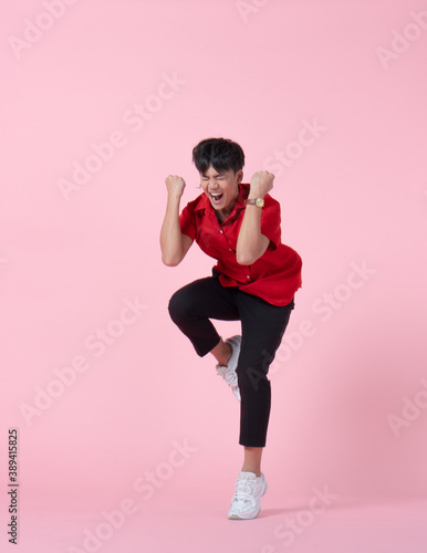 portrait of young handsome hipster asian man with smiling face wearing red shirt jumping on the pink background