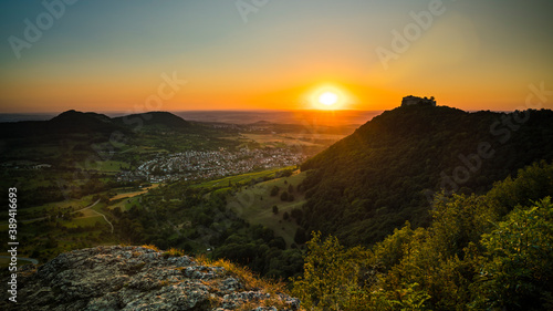 Germany, Scenic view above green valley of swabian alb Schwäbische Alb nature landscape and castle ruin of hohenneuffen on a mountain in warm sunset light