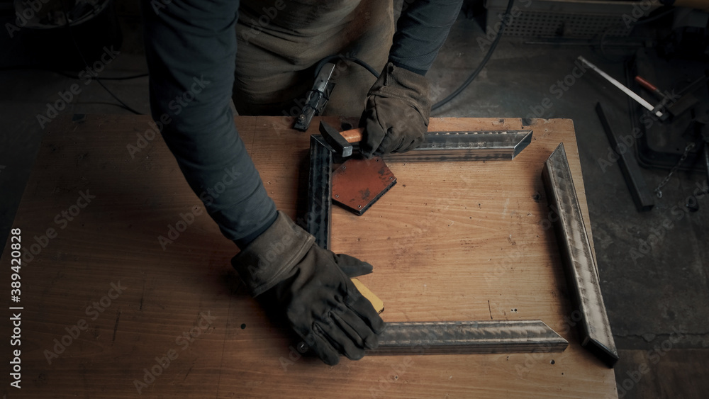 A welder in a protective suit puts the parts in the correct position. Top view A welder in a protective suit puts the parts in the correct position. Top view
