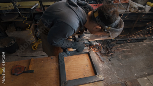 A man in gloves cuts metal with a circular saw, a lot of sparks. The working process