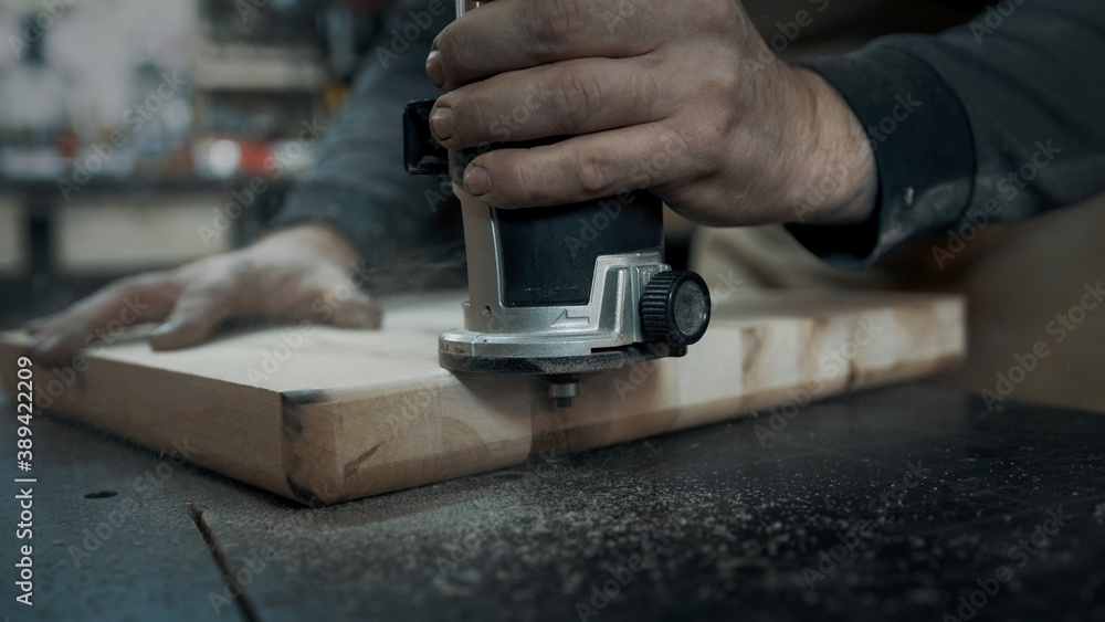 A carpenter mills the edges of a wood loft chair. A carpenter mills the edges of a wood loft chair.