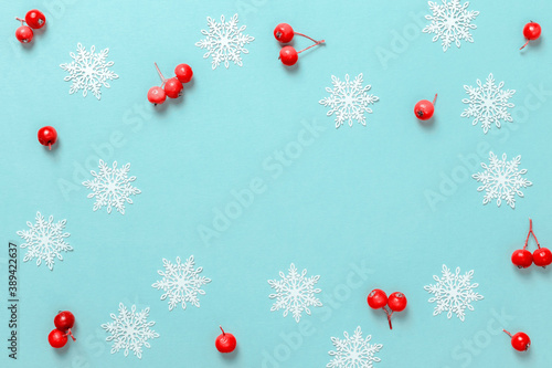 Holiday xmas background. White snowflakes, red berry in Christmas composition on pastel blue background for greeting card. Christmas, winter, new year concept.