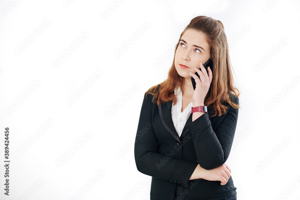 Portrait of pensive young businesswoman talking on phone and listening to complaints of client Portrait of pensive young businesswoman talking on phone and listening to complaints of client