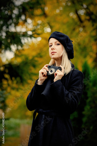 womna in black coat and hat with vintage camera in autumn park © Masson