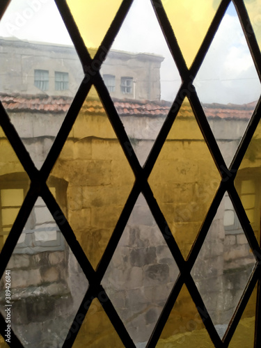 Watching out a stained glass window. Looking at the view of an old stone building