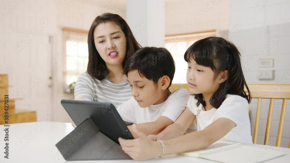 Happy Asia family homeschooling, mother teach children using digital tablet in living room at home. Spending time together, Self-isolation, Social distancing, Quarantine for corona virus prevention. Happy Asia family homeschooling, mother teach children using digital tablet in living room at home. Spending time together, Self-isolation, Social distancing, Quarantine for corona virus prevention.