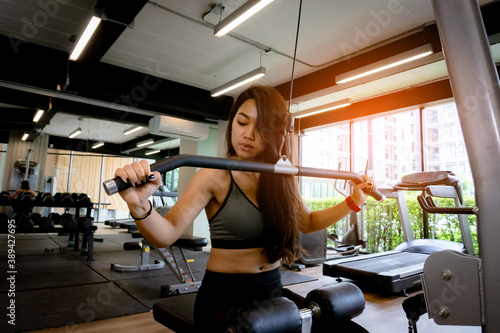 Young beautiful woman in sportswear working out with machine in gym