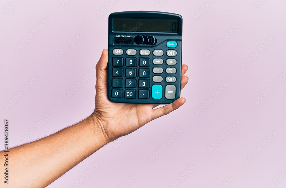 Hand of young hispanic man holding calculator over isolated pink background. Hand of young hispanic man holding calculator over isolated pink background.