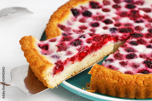 Closeup homemade berry pie with raspberry and blackberry on white wooden table. Shallow focus.