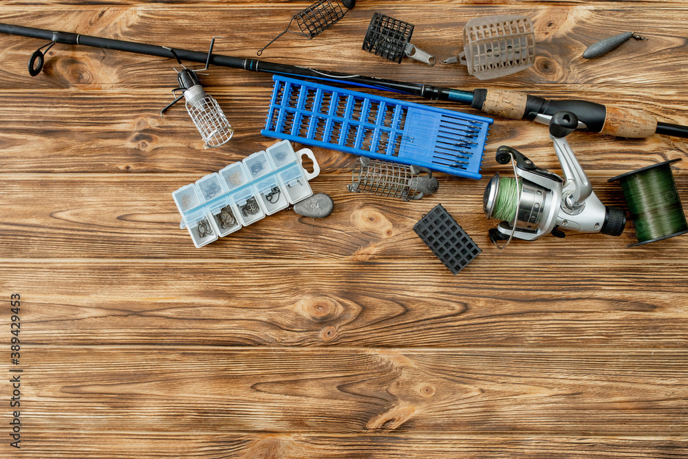 flat lay with fishing tackle, fishing rod and plastic box with fishing  tackle and hooks, feeders on wooden planks, copy space Stock Photo