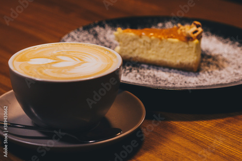 Cup of latte with curd cheesecake on dark wooden background